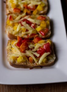 Grated cheese and chili flakes being sprinkled over buttered bread