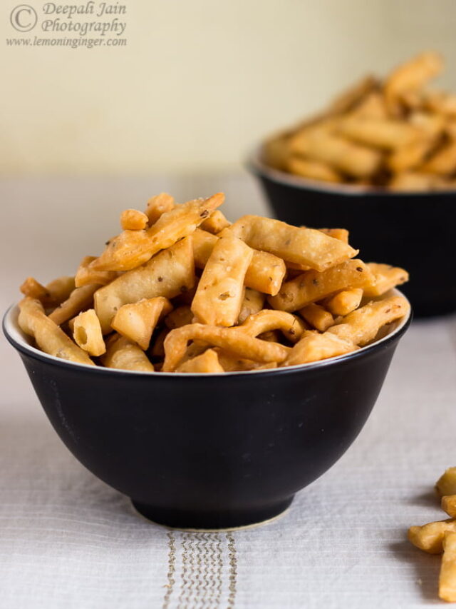 A bowl full of crispy, golden-brown Namak Para stacked neatly.
