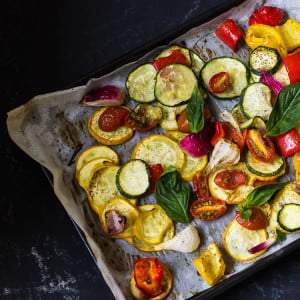 Oven-roasted vegetables served in a bowl with a side of lemon wedges