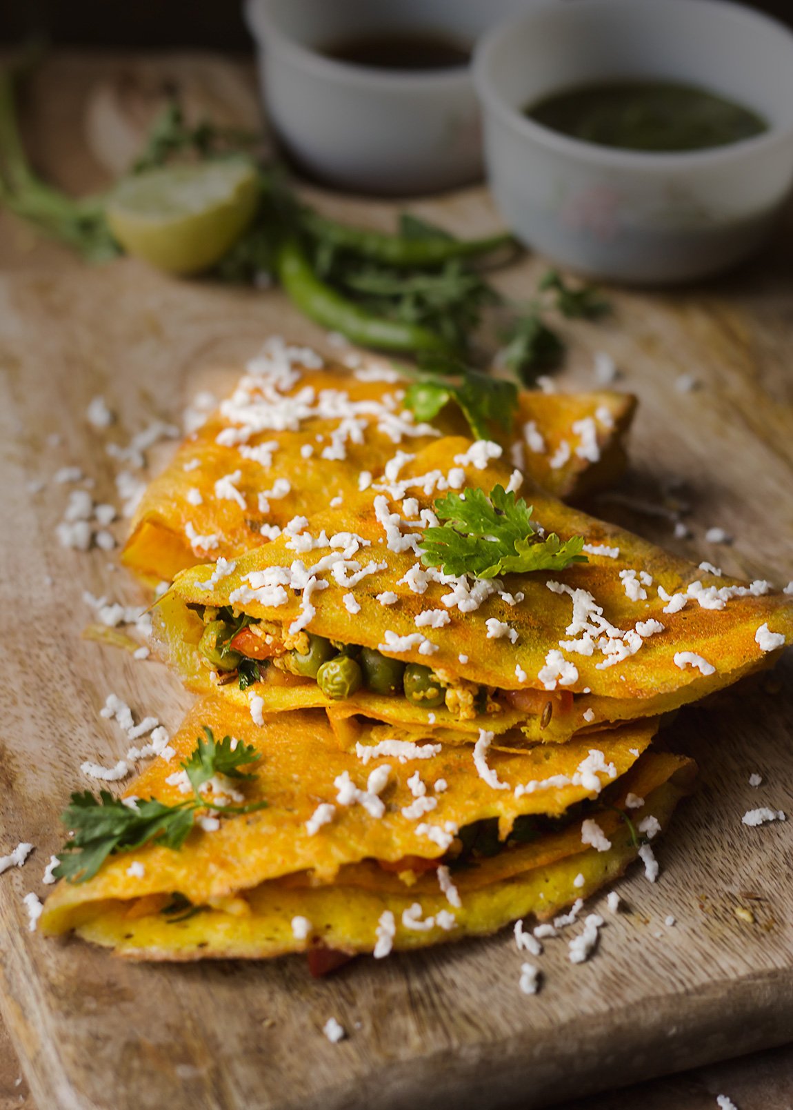 Stack of moong dal chillas served on a plate garnished with grated paneer
