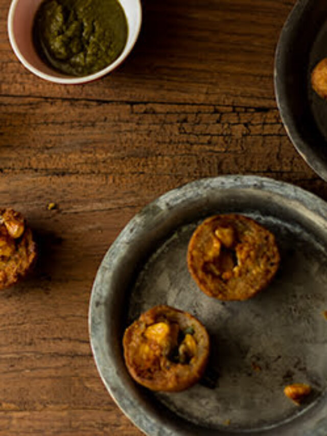 Close-up of the golden, flaky crust of a corn bread roll with a butter knife beside it