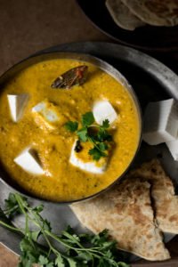 Kadai Paneer plated beautifully with roti and sliced onions on a wooden table
