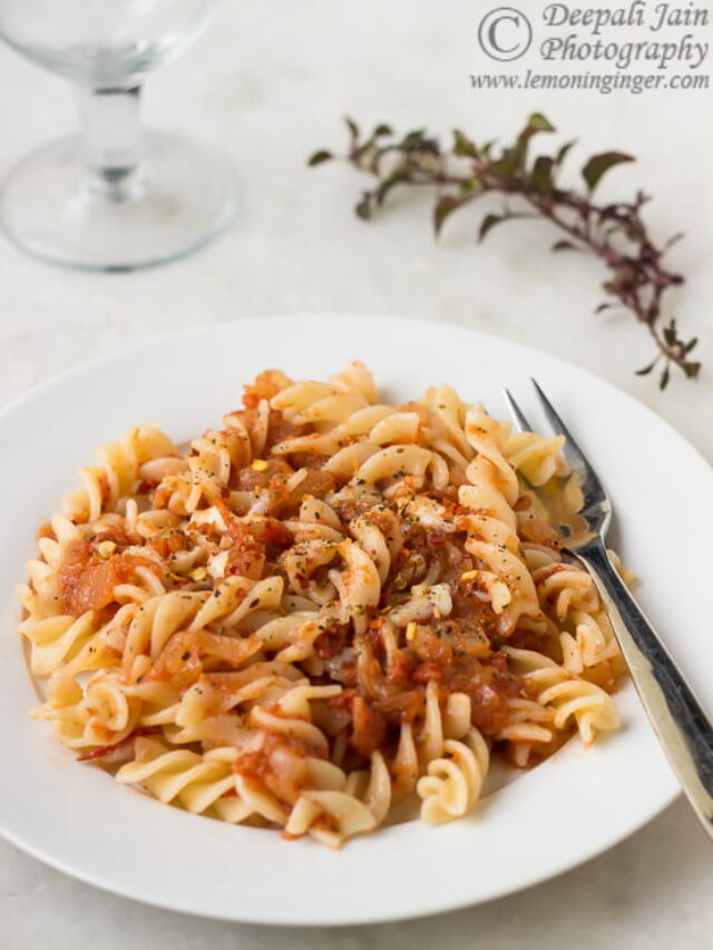 Close-up of pasta twirled around a fork, drenched in pizza sauce