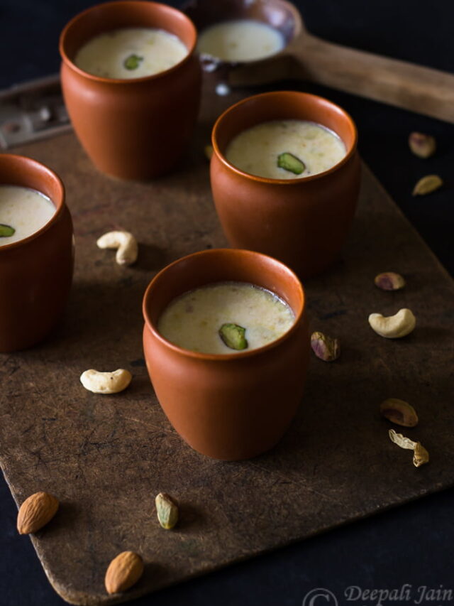 Masala Doodh (Masala Milk) topped with a sprinkle of spices and garnished with slivered almonds