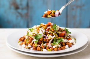 A spoonful of sprouted moong salad showing a mix of fresh vegetables and sprouts.