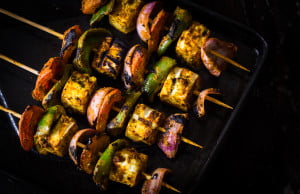 Vibrant paneer tikka served with onion rings, lemon wedges, and green chutney