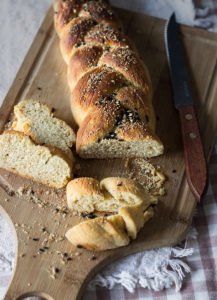 Close-up of freshly baked golden brown braided challah bread on a wooden board