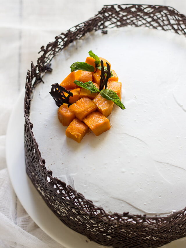 Eggless mango white cake topped with fresh mango slices and mint leaves