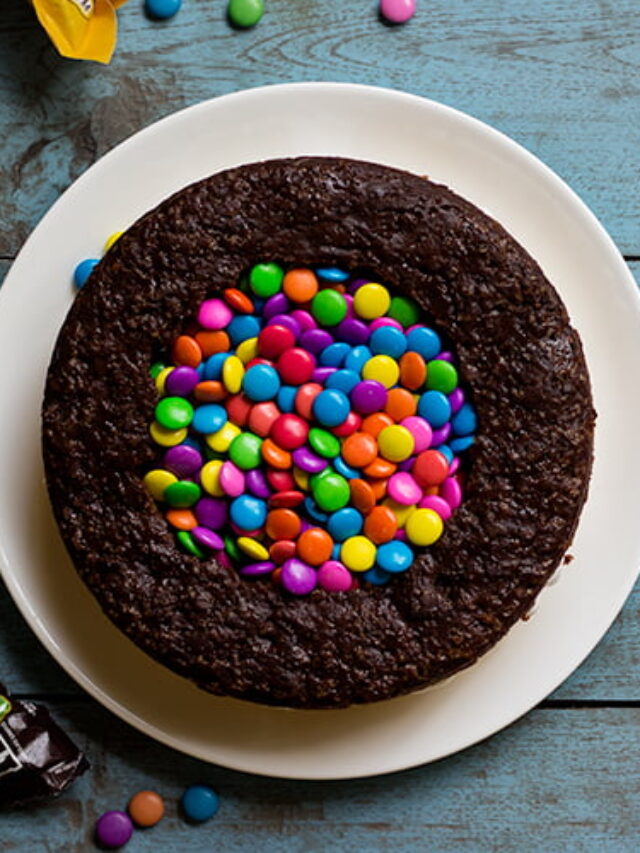 A beautifully decorated M&M Pinata Cake with a rainbow of M&Ms on top