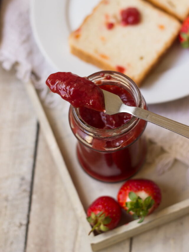 Thick strawberry jam cooling in a glass jar