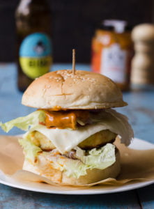 Close-up of a crispy paneer tikka burger with a golden-brown paneer patty