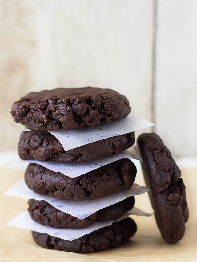 A stack of freshly baked double chocolate chip cookies on a cooling rack