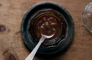 Close-up of Tamarind Chutney drizzling off a spoon, highlighting its thick and smooth texture