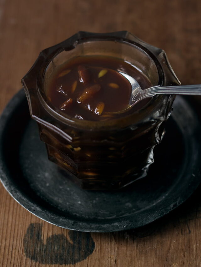 A jar of homemade Sweet Imli Chutney with a spoon sticking out, ready to be used