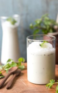 Glass of chilled masala buttermilk garnished with coriander and cumin