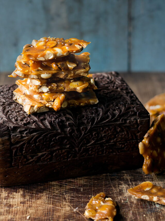 Close-up of golden brown peanut brittle pieces stacked on the box