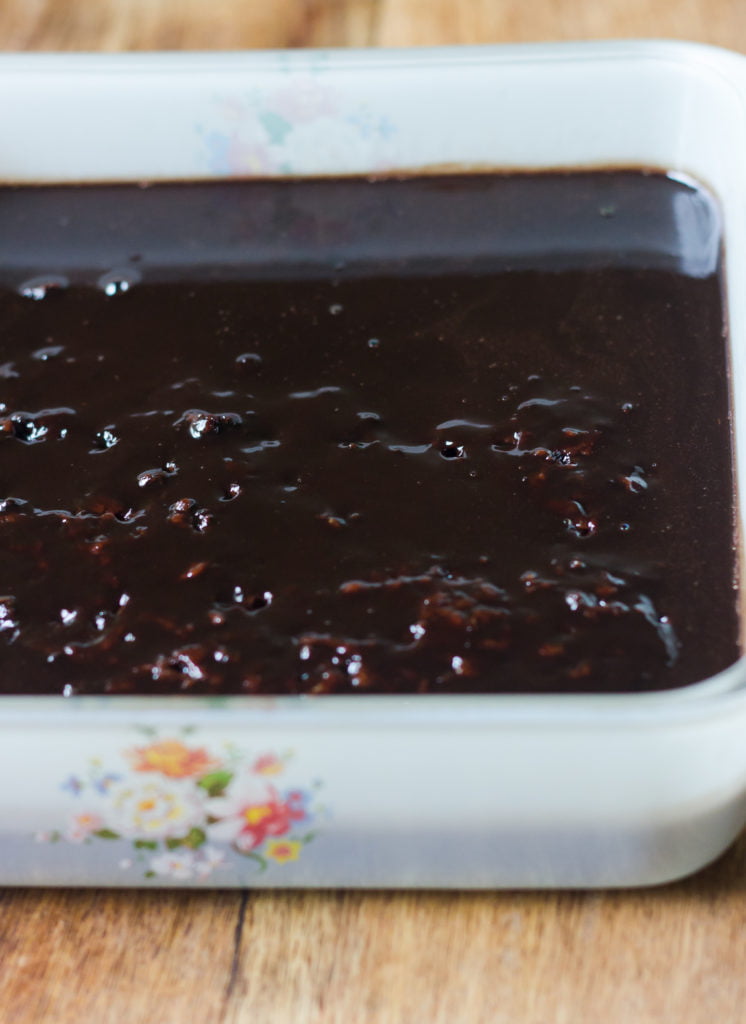 The whiskey and coffee syrup being poured into poke holes in the cake