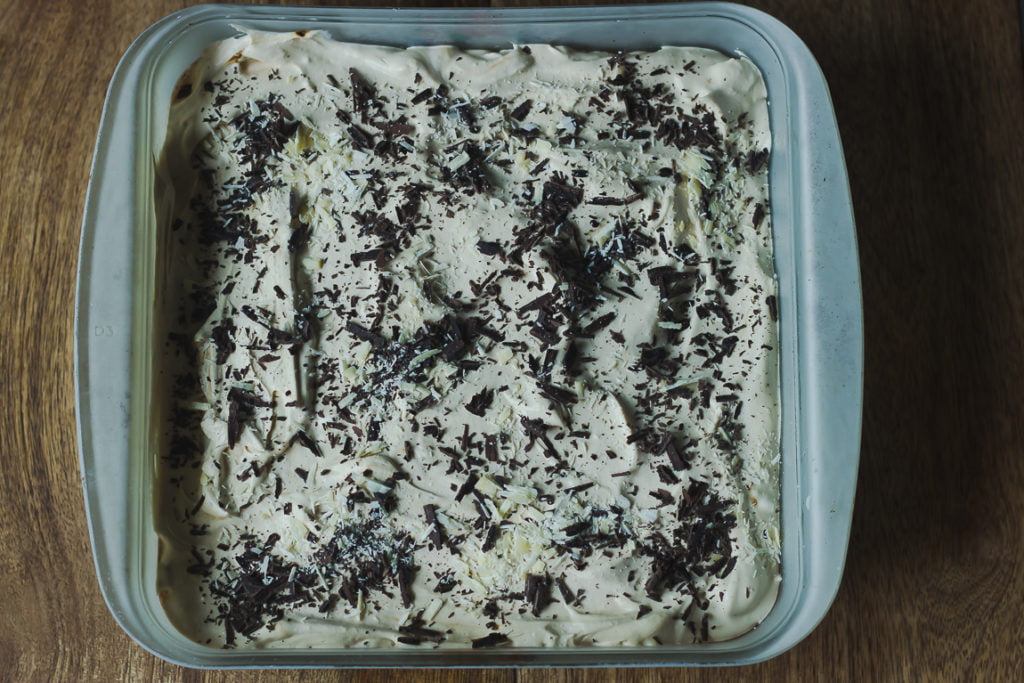 Overhead shot of the finished Eggless Whiskey Coffee Poke Cake garnished with cream
