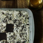 Eggless Whiskey Coffee Poke Cake topped with whipped cream and chocolate curls