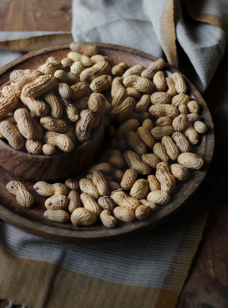 A plate and a bowl filled with raw peanuts