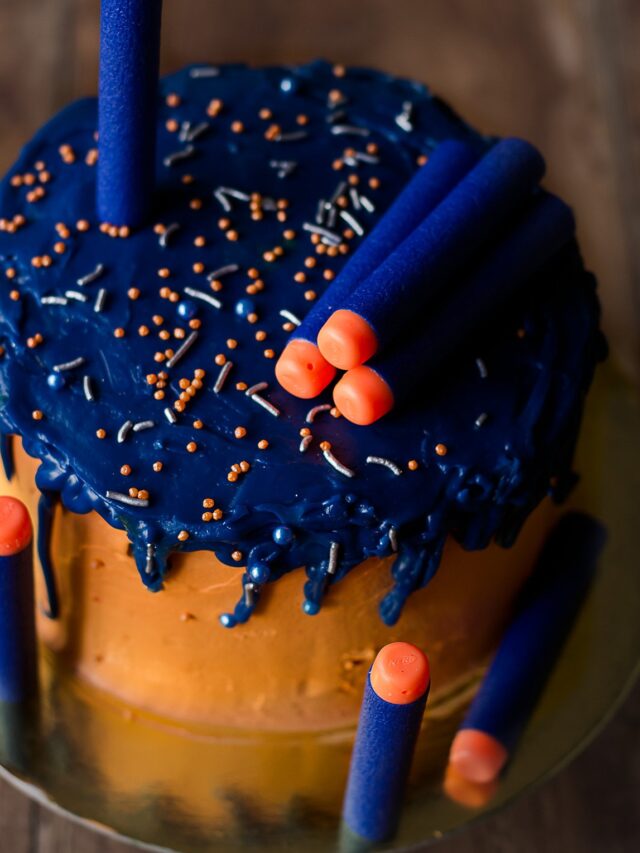 A vibrant and colorful Eggless Nerf Gun Cake decorated with colored chocolate drip