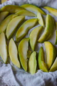 Slices of raw mangoes kept on a cloth to dry