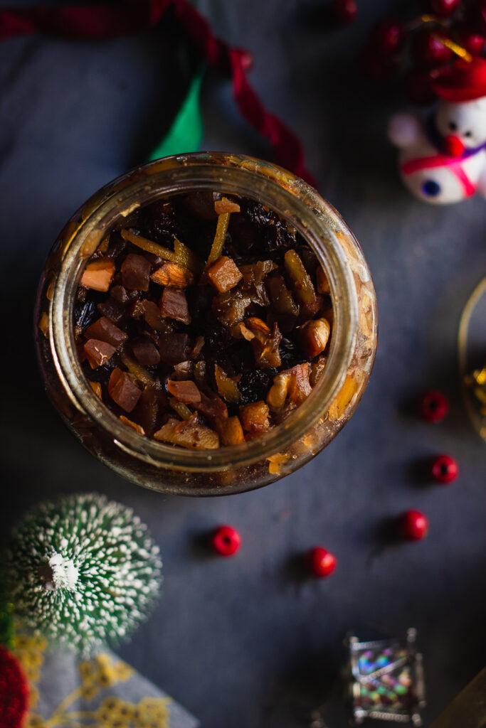 A mason jar filled with colorful dried fruits soaking for traditional fruit cake