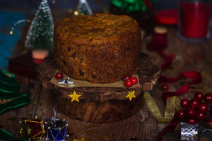 Brandied Christmas fruit cake on a festive platter with holiday decorations in the background